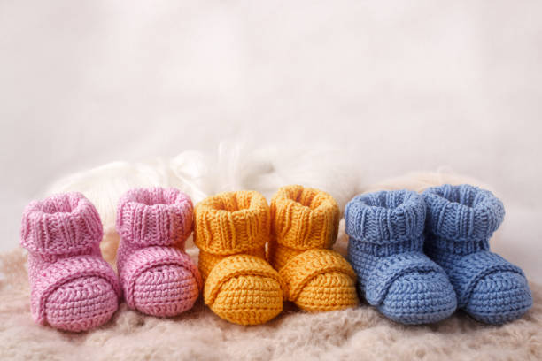 pregnancy concept, Three pairs of baby booties on a light background pregnancy concept, Three pairs of baby booties on a light background baby booties stock pictures, royalty-free photos & images