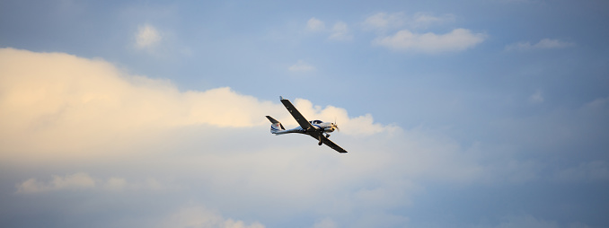 Small plane on blue cloudy sky background