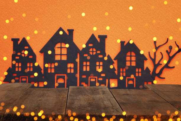 istock Halloween holiday concept. Empty rustic table in front of haunted village over orange background. Ready for product display montage. 1030882172