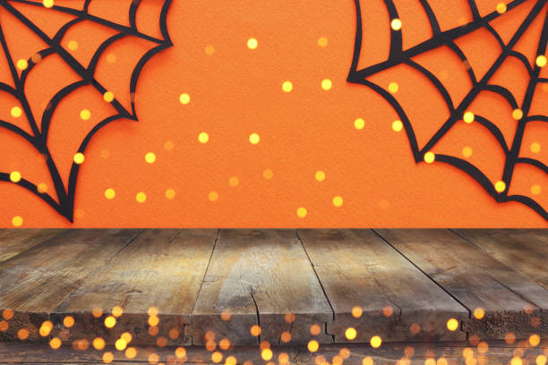 istock Halloween holiday concept. Empty rustic table in front of Spider webs over orange background. Ready for product display montage. 1030882182