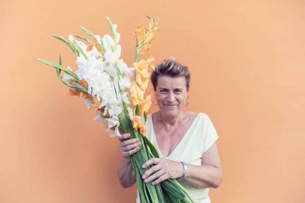 senior dame avec bouquet de fleurs de glaïeul blanc et orange. - flower purple gladiolus isolated photos et images de collection