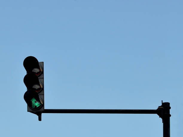 istock Green traffic light installed on a pole above a roadway, against a blue sky 1030883574