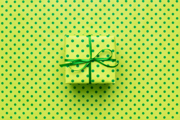 Green gift box on wrapping paper with polka dots. Minimal background for card, flyer, invitation, placard or voucher.