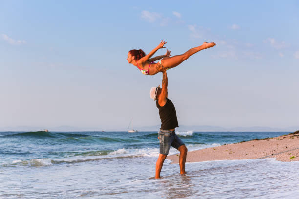 istock Two Flexible Circus Performers, male and female acrobat practicing gymnastics on the beach by the sea in the morning, on a sand beach. 1030897484