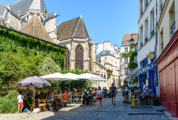 einer kleinen gepflasterten fußgängerzone im alten stadtteil von le marais in paris, frankreich, hinter saint-gervais kirche, mit dem mittagessen auf der terrasse eines restaurants mit einem sonnigen sommertag. - places of worship europe france paris france stock-fotos und bilder