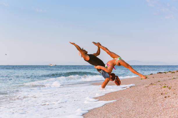 istock Two Flexible Circus Performers, male and female acrobat practicing gymnastics on the beach by the sea in the morning, on a sand beach. 1030898868