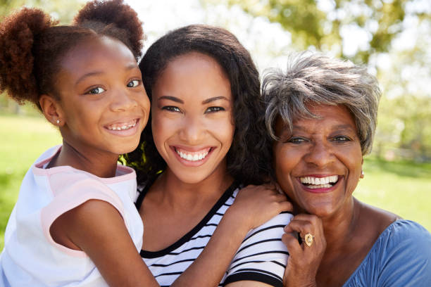 ritratto di nonna con figlia adulta e nipote rilassante nel parco - grandmother senior adult smiling women foto e immagini stock