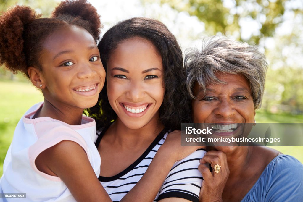 Portrait Of Grandmother With Adult Daughter And Granddaughter Relaxing In Park Family Stock Photo
