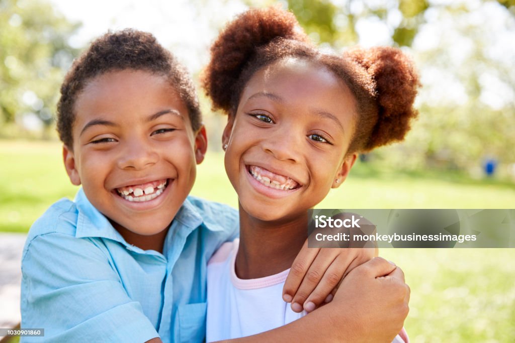 Portrait Of Brother And Sister Relaxing In Park Together Sibling Stock Photo