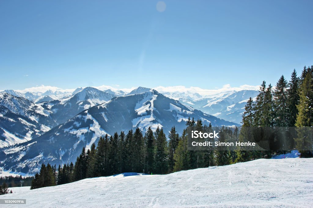 view on the mountains from a ski piste Contrastful mountains and trees in front of a blue sky seen from a ski piste in austria during daylight Austria Stock Photo
