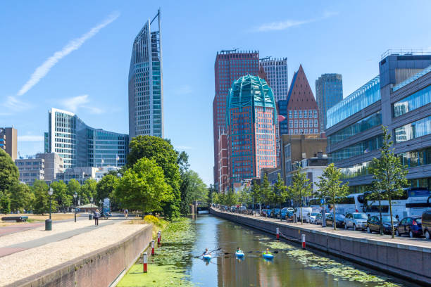 sunny city skyline with Kayakers paddling on canal The Hague, the Netherlands - July 12 2018: sunny modern skyline of the city of The Hague with recreational kayakers paddling a scenic canal binnenhof photos stock pictures, royalty-free photos & images