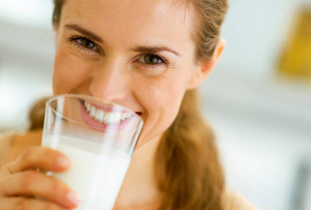 sonriendo la leche de consumo joven - mujer bebiendo leche fotografías e imágenes de stock