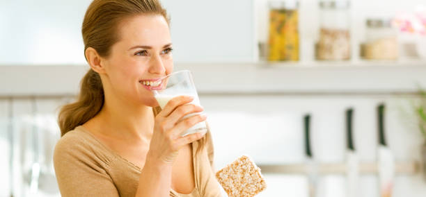 istock Young woman eating crisp bread with milk and looking on copy spa 1030907638