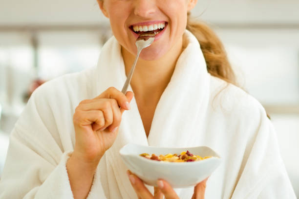 istock Smiling young woman in bathrobe eating healthy breakfast 1030907772