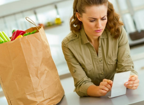 istock Concerned housewife checking bill after shopping in kitchen 1030907918