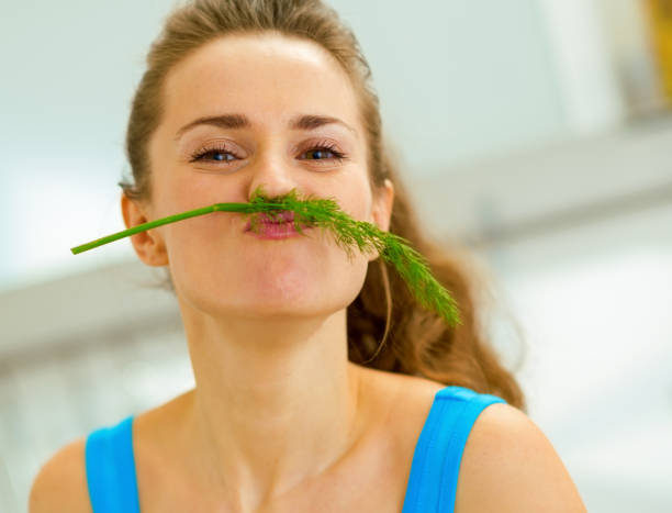 istock Funny young woman using dill as mustache in kitchen 1030912330