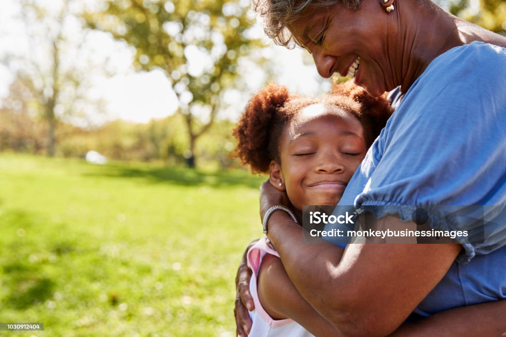 Close Up Of Granddaughter Hugging Grandmother In Park Grandmother Stock Photo
