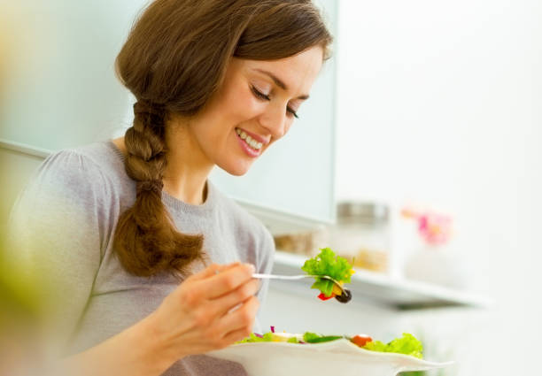 istock Young woman eating fresh salad in modern kitchen 1030912740