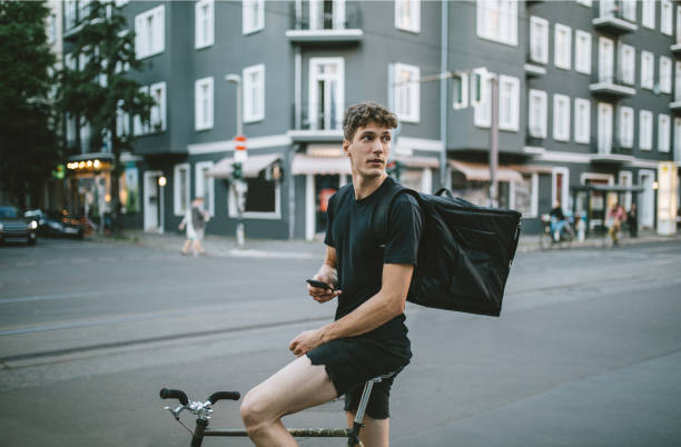 male bike courier checking his phone. - bicycle messenger imagens e fotografias de stock