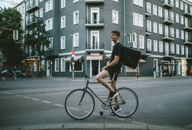 Hipster commuter on his bicycles. He is standing on his bike smiling and looking into the camera.
