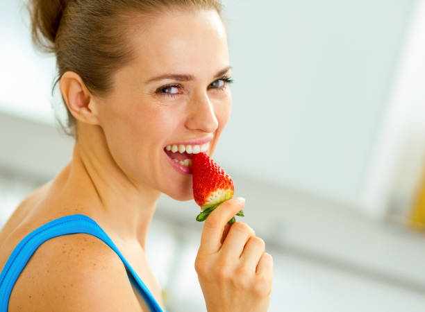 istock happy young woman eating strawberry 1030912810