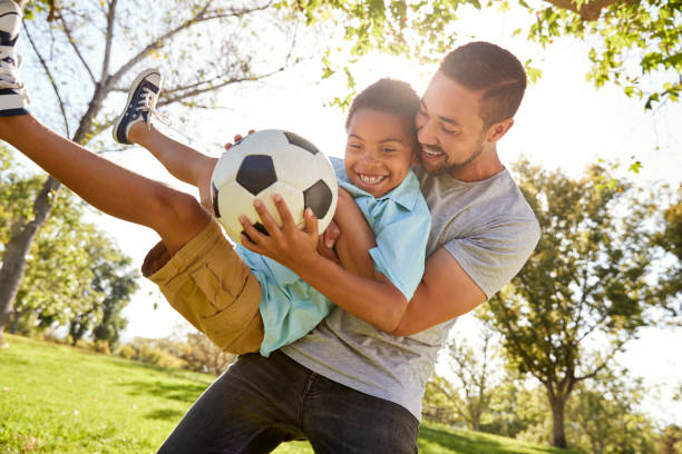 padre e hijo jugando al fútbol en el parque juntos - sports equipment fotos fotografías e imágenes de stock