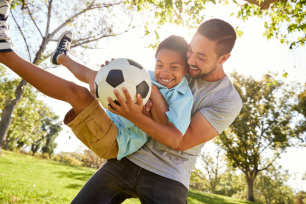 ojciec i syn gra w piłkę nożną w parku razem - father son ethnic child zdjęcia i obrazy z banku zdjęć