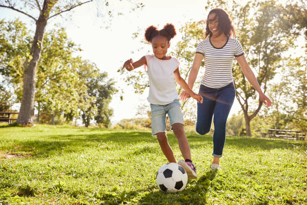 madre e hija jugando al fútbol en el parque juntos - people caucasian sport family fotografías e imágenes de stock