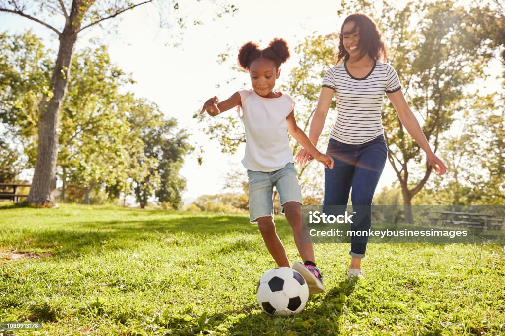 Mother And Daughter Playing Soccer In Park Together Child Stock Photo