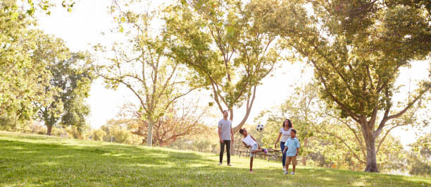 famiglia che gioca a calcio nel parco insieme - family fun running couple foto e immagini stock