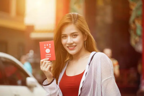 Photo of beautiful Young Asian women tourist traveler with backpack smiling and show passport of Japan in China town  market culture