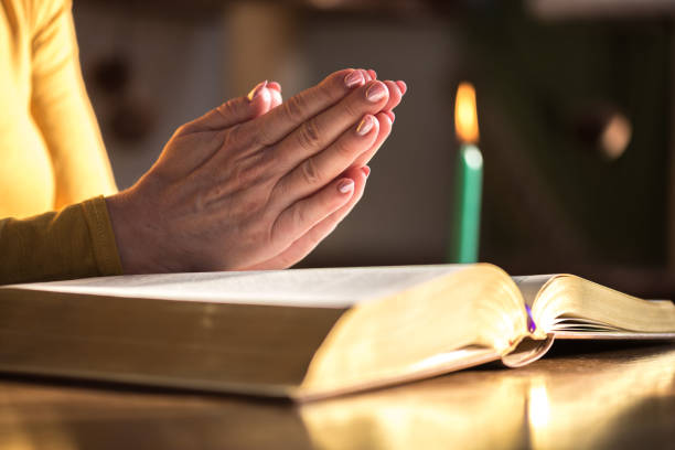 istock Woman praying with her hands over the bible, hard light 1030916978