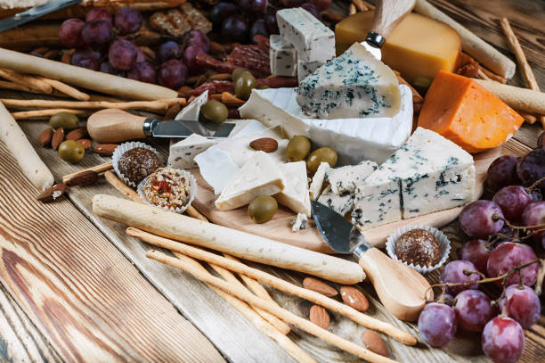 verschiedene arten von käse und trauben auf einem hölzernen hintergrund. close-up - cheese emmental cheese swiss culture cutting board stock-fotos und bilder