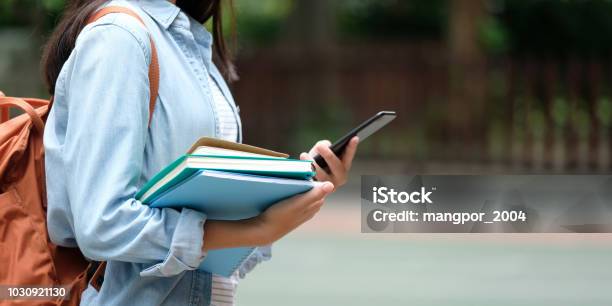 Studentin Halten Bücher Und Smartphone Während Des Gehens In Schule Campus Hintergrund Bildung Zurück Zum Schulkonzept Stockfoto und mehr Bilder von Universität