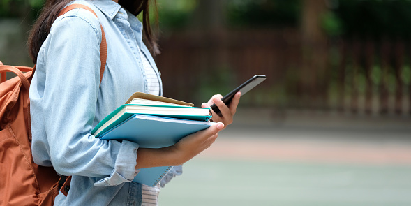 Chica estudiante con libros y smartphone mientras camina en el fondo del campus de escuela, educación, regresar al concepto de escuela photo