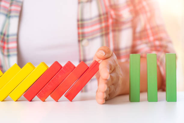 istock Solution concept with hand stopping wooden blocks from falling in the domino line. 1030921814