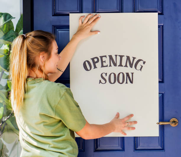 istock Woman putting on store opening soon sign 1030934338