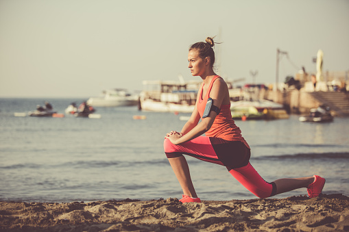 Copy space shot of a young woman doing stretching exercises by the sea.