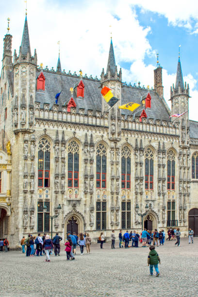 Tourists in the Grand Place and in the background the Bruges Town Hall.