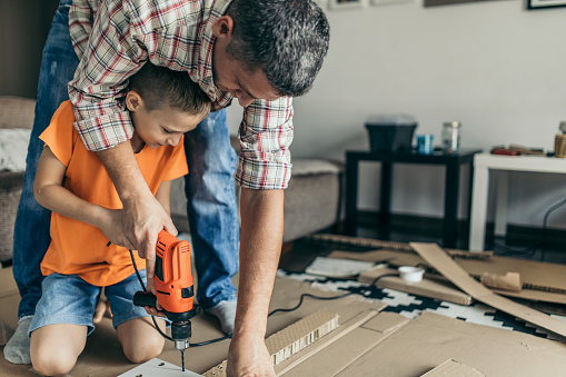 Single father is assembling furniture with his kids