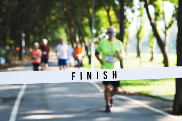 hombre maduro corriendo hacia la línea de meta - finish line fotografías e imágenes de stock