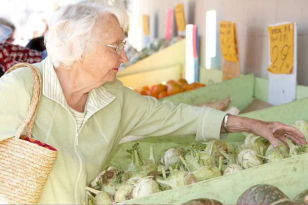 senior woman picking out vegetables at fruitstand. - fruitstand - fotografias e filmes do acervo