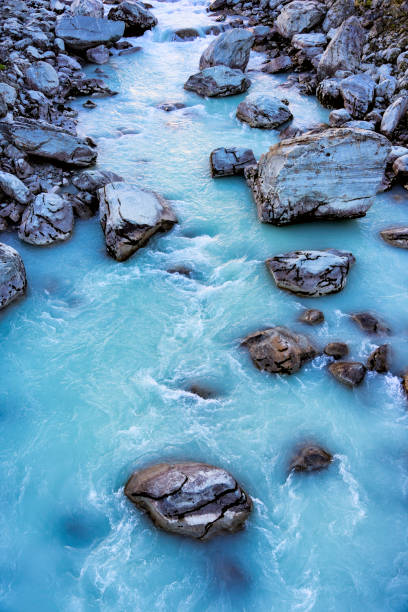 Looking down onto great rocks and boulders caught in the fast flowing and alluvial-blue waters of the Hooker River, in the Mt Cook National Park