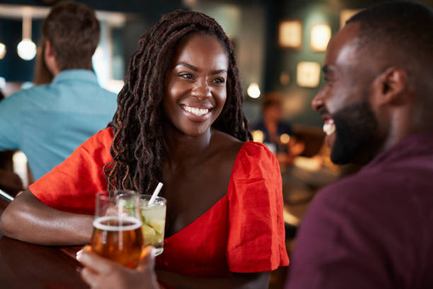 pareja en fecha sentado en barra de bar y hablar - cocktail alcohol drink black fotografías e imágenes de stock