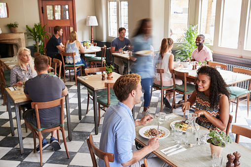 Customers Enjoying Meals In Busy Restaurant