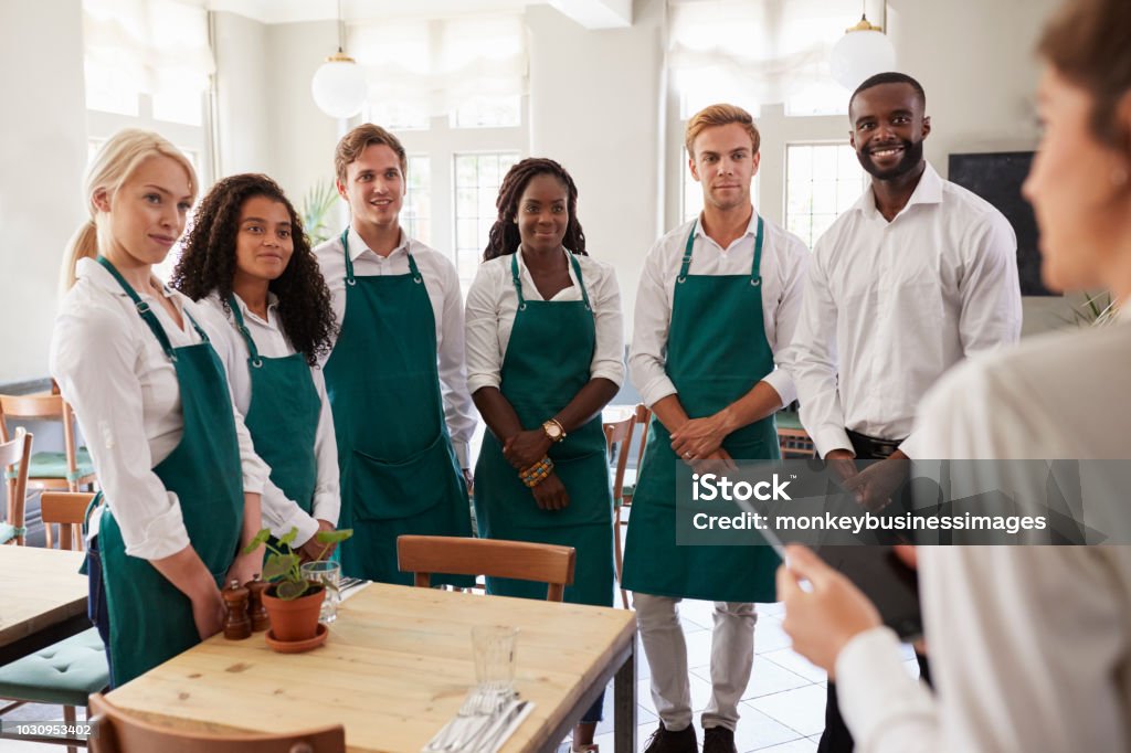 Staff Attending Team Meeting In Empty Dining Room Restaurant Stock Photo