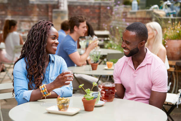 coppia seduta a tavola nel giardino del pub godendosi da bere insieme - giardino di birra foto e immagini stock