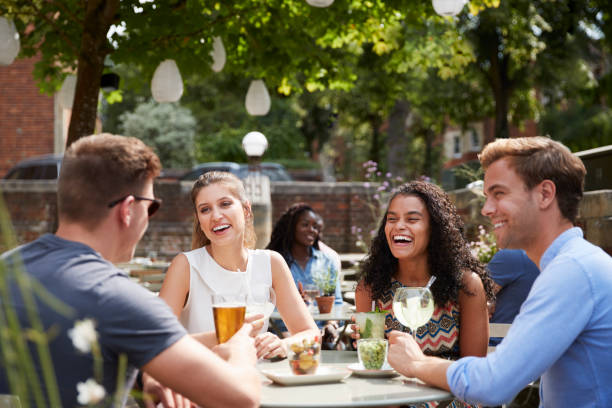 istock Friends Sitting At Table In Pub Garden Enjoying Drinks Together 1030957348
