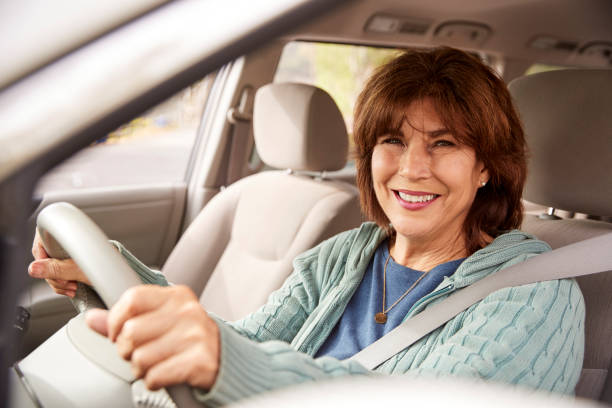 starsza kobieta w foteliku samochodowym patrząc na kamerę, z bliska - driving senior adult car women zdjęcia i obrazy z banku zdjęć