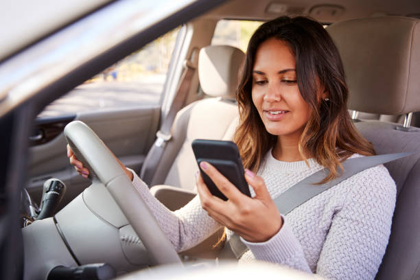 istock Young woman in car checking her smartphone while driving 1030961348